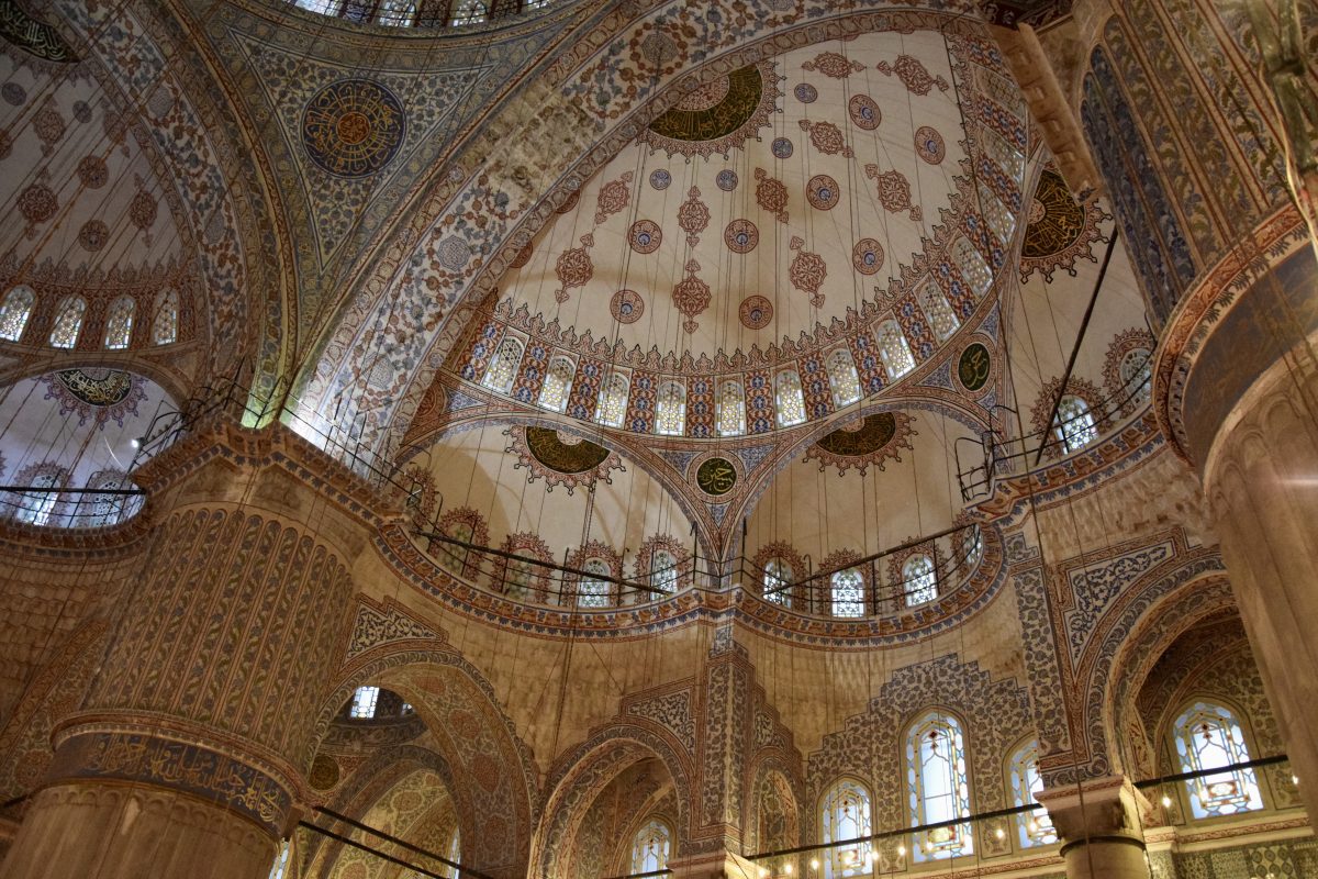 A view upwards towards the domes of a mosque, taking in all the intricate artistic details.