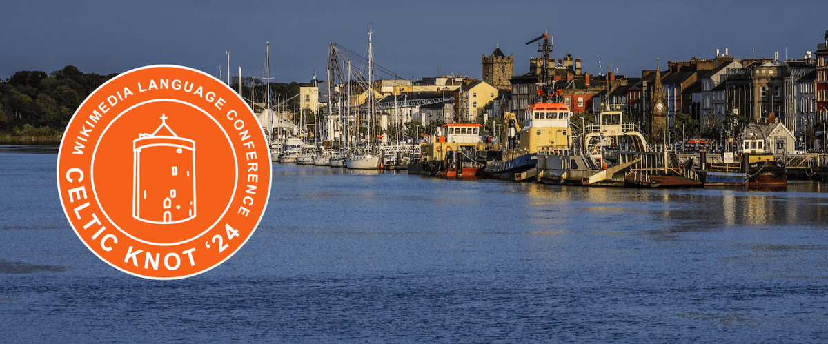 Photograph of boats along a river that runs through the city of Waterford with an orange version of the 2024 Celtic Knot logo